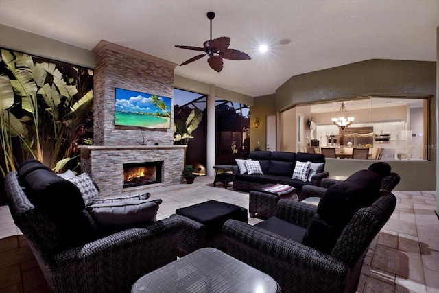 living room featuring lofted ceiling, ceiling fan with notable chandelier, and an outdoor stone fireplace