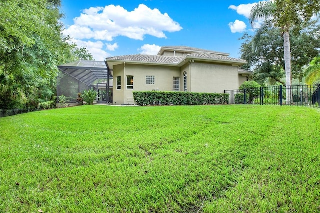 rear view of house featuring a yard and glass enclosure