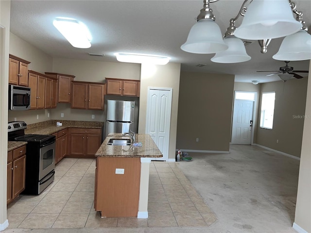 kitchen with ceiling fan, light stone countertops, sink, an island with sink, and stainless steel appliances