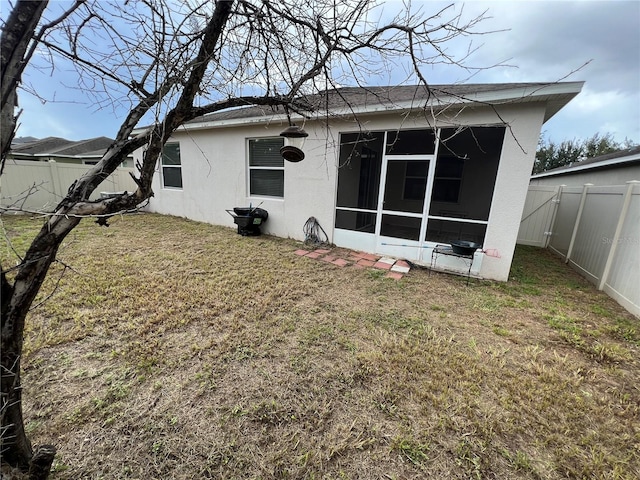 rear view of house featuring a sunroom and a lawn