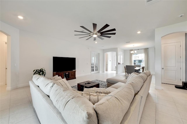 living room featuring light tile flooring and ceiling fan with notable chandelier