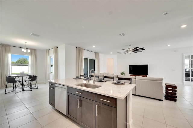 kitchen featuring sink, light tile flooring, dishwasher, and a center island with sink