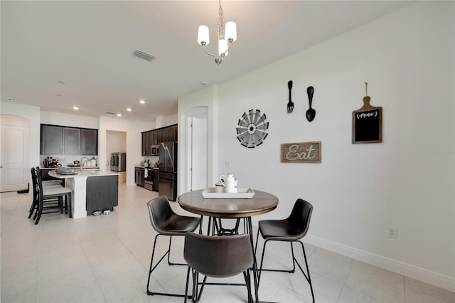 dining space with a notable chandelier, sink, and light tile floors