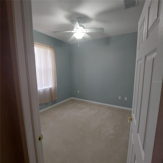 carpeted spare room featuring ceiling fan and a textured ceiling