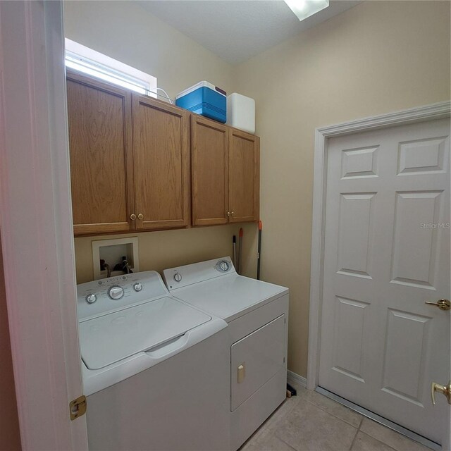 laundry area with cabinets, light tile patterned floors, and washing machine and dryer