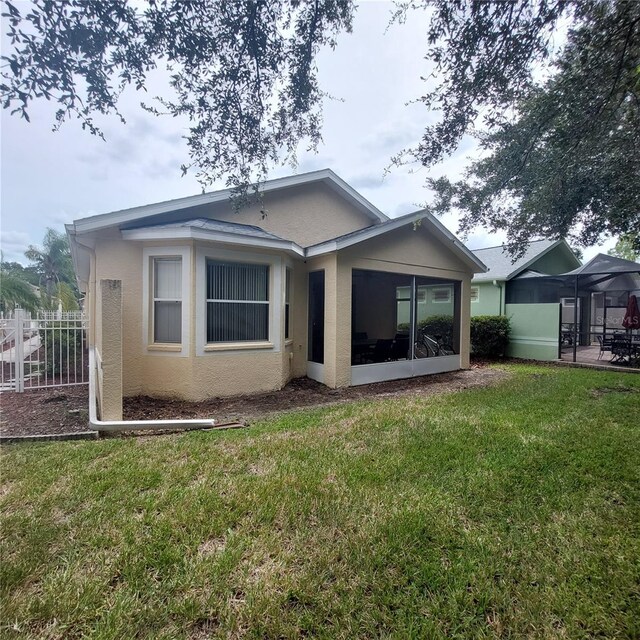 rear view of house featuring a sunroom and a yard