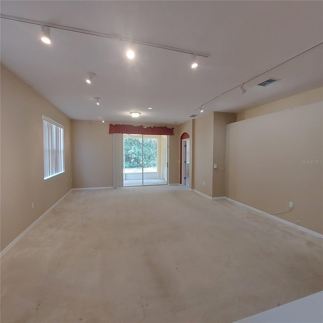 unfurnished room featuring light carpet and track lighting