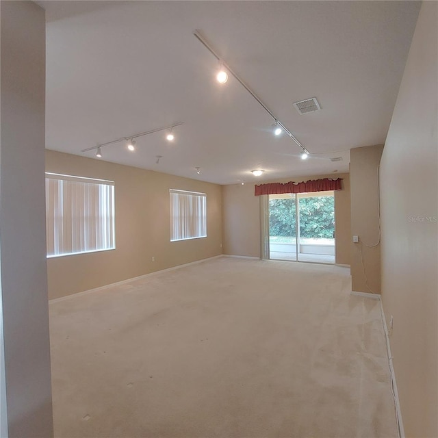 carpeted empty room featuring rail lighting