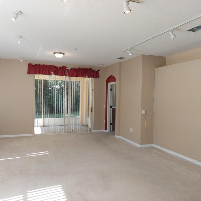 8049 Sanguinelli Rd, Land O Lakes, FL 34637 - unfurnished room with track lighting, arched walkways, light carpet, and baseboards