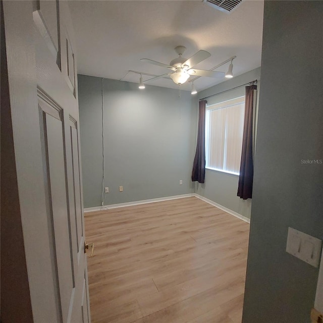 spare room with ceiling fan, track lighting, and light hardwood / wood-style flooring