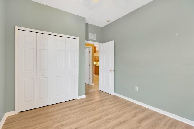 8049 Sanguinelli Rd, Land O Lakes, FL 34637 - unfurnished bedroom featuring baseboards, light wood-style flooring, a closet, a high ceiling, and a ceiling fan