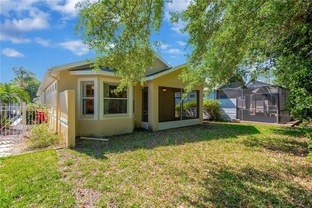 8049 Sanguinelli Rd, Land O Lakes, FL 34637 - rear view of property featuring stucco siding, a lawn, and a sunroom