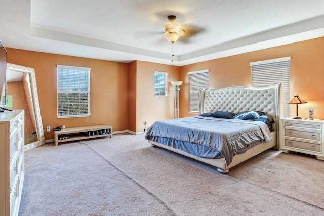 carpeted bedroom featuring a raised ceiling and ceiling fan