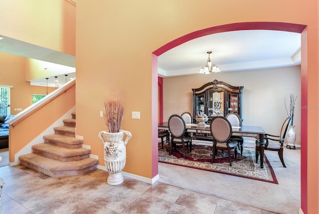 tiled dining room with a raised ceiling and a chandelier