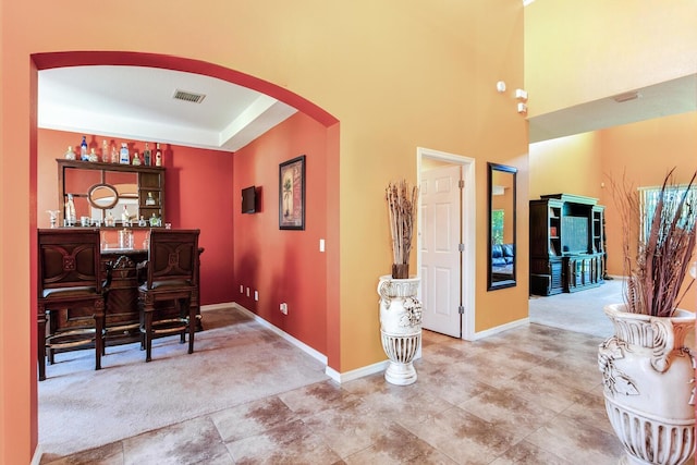 dining area with light tile floors, a tray ceiling, and indoor bar