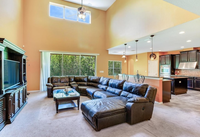 carpeted living room featuring a wealth of natural light, ceiling fan, and a high ceiling