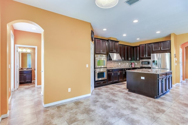 kitchen featuring appliances with stainless steel finishes, dark brown cabinets, light tile flooring, and light stone counters