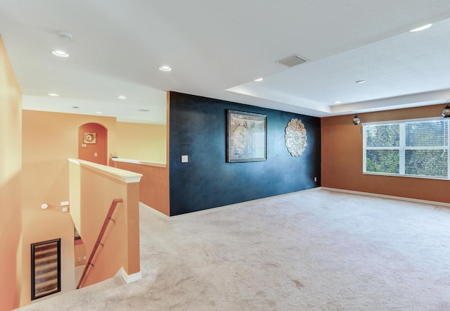 unfurnished room featuring light colored carpet and a tray ceiling