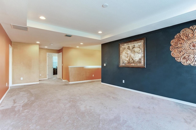 carpeted spare room featuring a raised ceiling