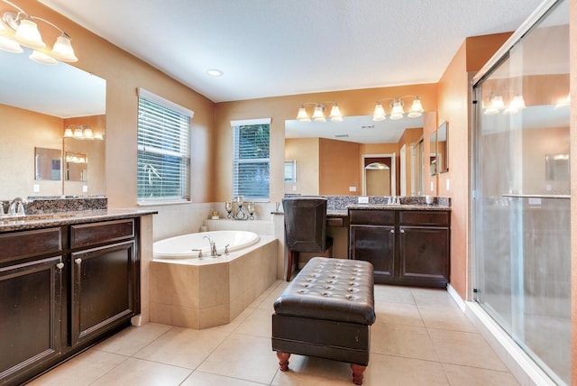 bathroom with a textured ceiling, plus walk in shower, vanity with extensive cabinet space, and tile flooring