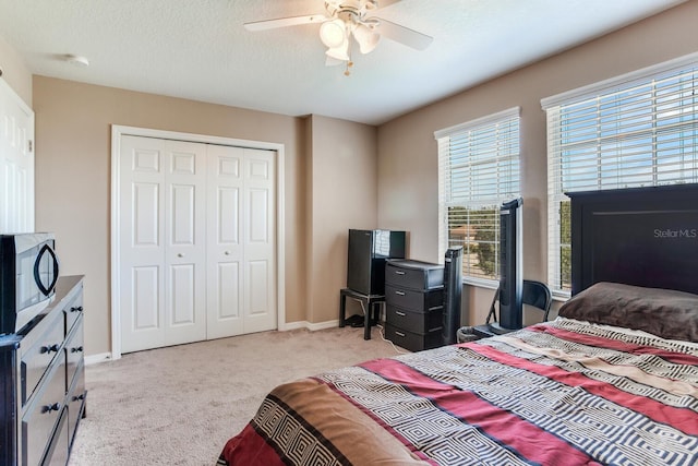 carpeted bedroom featuring a closet, ceiling fan, and a textured ceiling