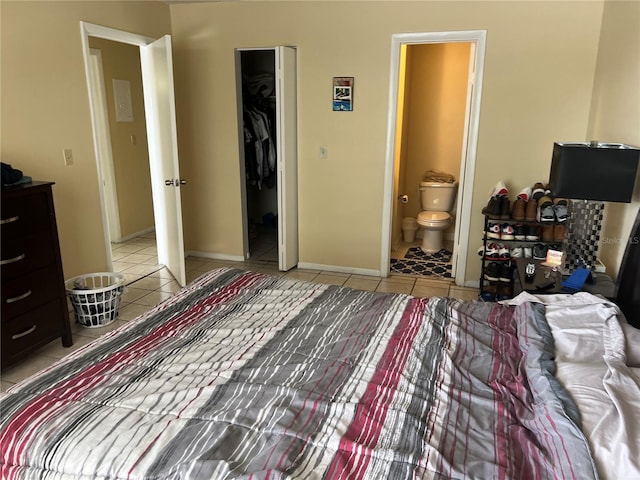 tiled bedroom with a spacious closet, a closet, and ensuite bathroom