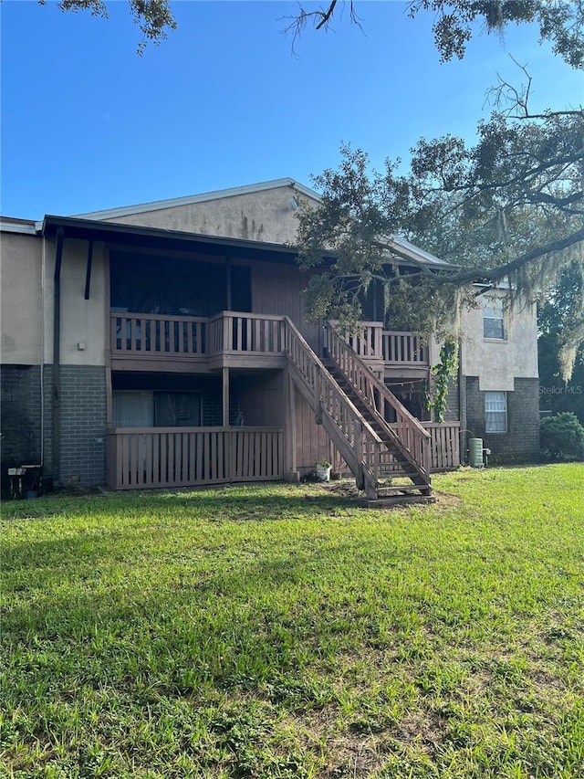 rear view of house featuring a lawn and a wooden deck