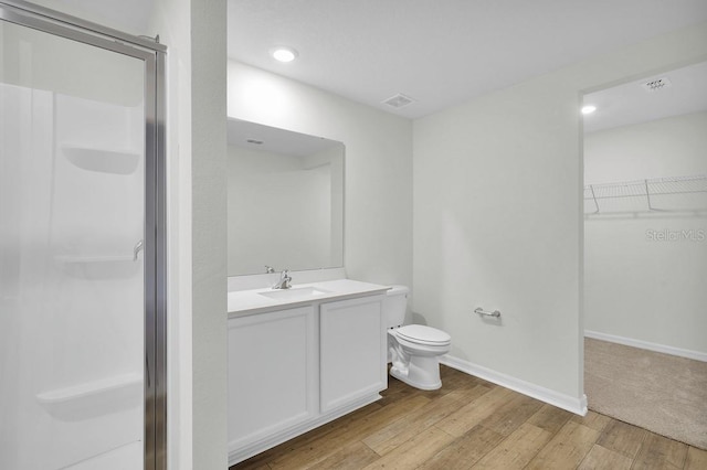 bathroom with a shower with shower door, wood-type flooring, toilet, and large vanity