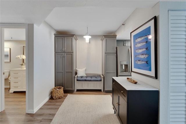 interior space featuring stainless steel fridge with ice dispenser, hanging light fixtures, light hardwood / wood-style floors, and gray cabinets