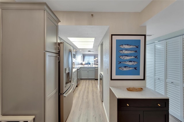 kitchen with a skylight, light stone counters, light hardwood / wood-style flooring, and stainless steel appliances