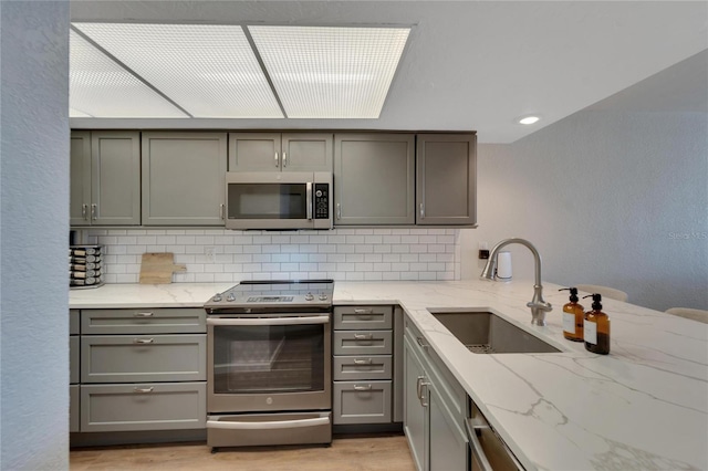 kitchen featuring gray cabinetry, stainless steel appliances, sink, and light wood-type flooring