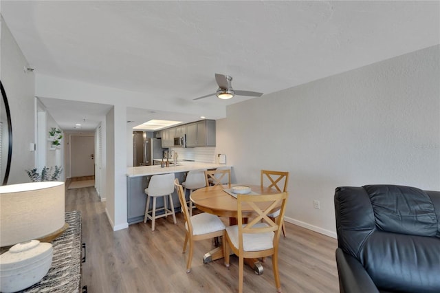 dining area featuring light hardwood / wood-style flooring, sink, and ceiling fan