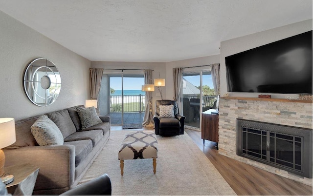 living room with a wealth of natural light, wood-type flooring, a fireplace, and a water view