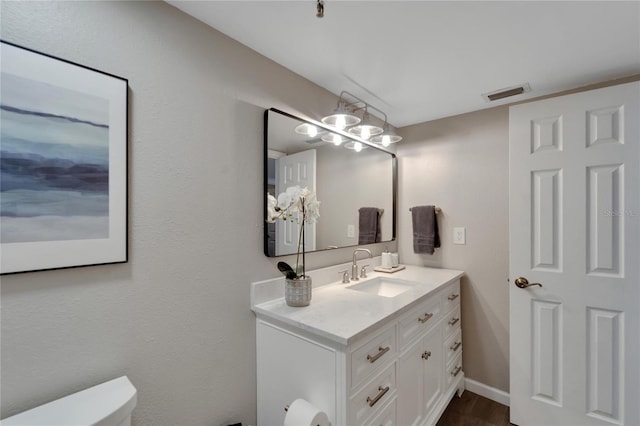 bathroom featuring hardwood / wood-style floors, vanity, toilet, and a notable chandelier