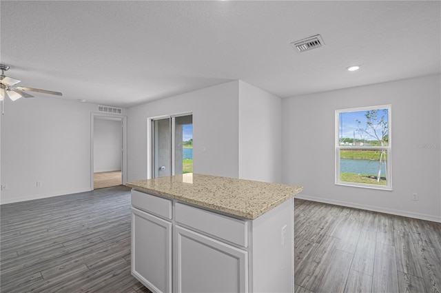 kitchen with a wealth of natural light, dark wood-type flooring, white cabinets, and a center island