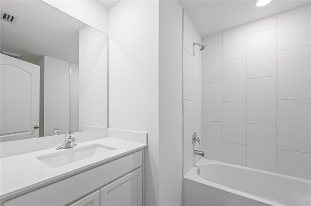 bathroom featuring vanity, tiled shower / bath combo, and a textured ceiling