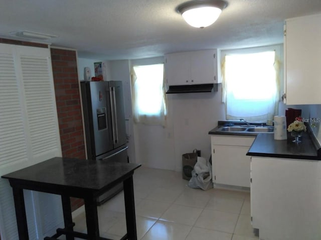 kitchen with stainless steel fridge, light tile flooring, white cabinets, and sink