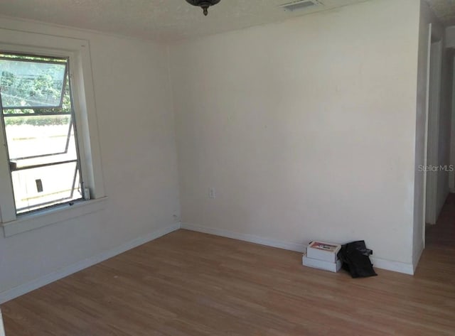 empty room with a textured ceiling, wood-type flooring, and a wealth of natural light