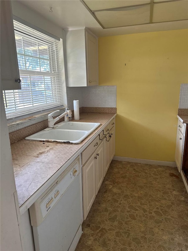 kitchen with sink, dark tile flooring, white cabinets, backsplash, and white dishwasher