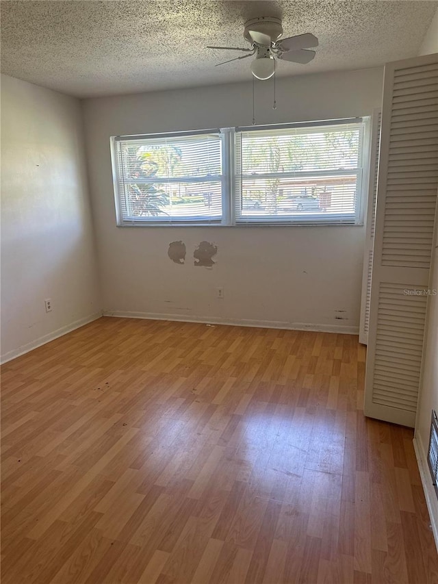 unfurnished room featuring a textured ceiling, ceiling fan, light wood-type flooring, and a wealth of natural light