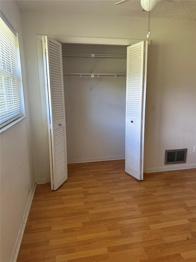 unfurnished bedroom featuring a textured ceiling, light hardwood / wood-style floors, and ceiling fan