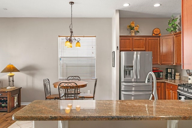 kitchen featuring dark stone countertops, light hardwood / wood-style flooring, a notable chandelier, and appliances with stainless steel finishes