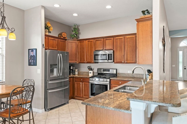 kitchen featuring kitchen peninsula, light stone countertops, sink, and stainless steel appliances