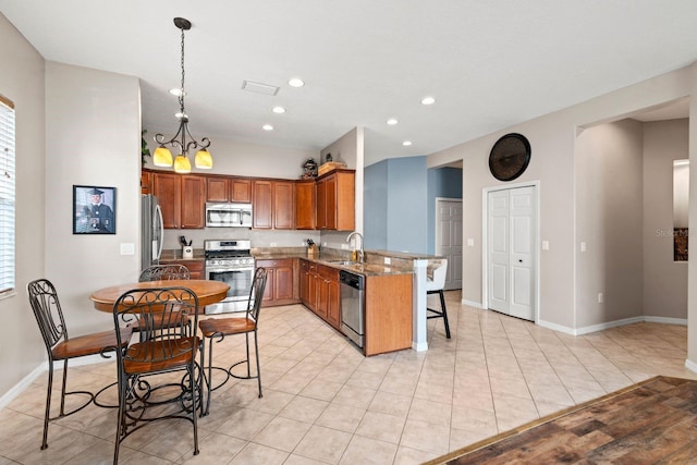 kitchen with kitchen peninsula, light stone countertops, stainless steel appliances, a chandelier, and hanging light fixtures