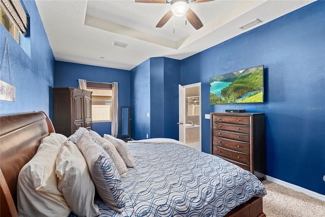 bedroom with ceiling fan, a raised ceiling, carpet floors, and connected bathroom