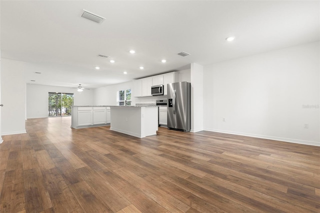 kitchen featuring white cabinets, a center island, light stone counters, and stainless steel appliances