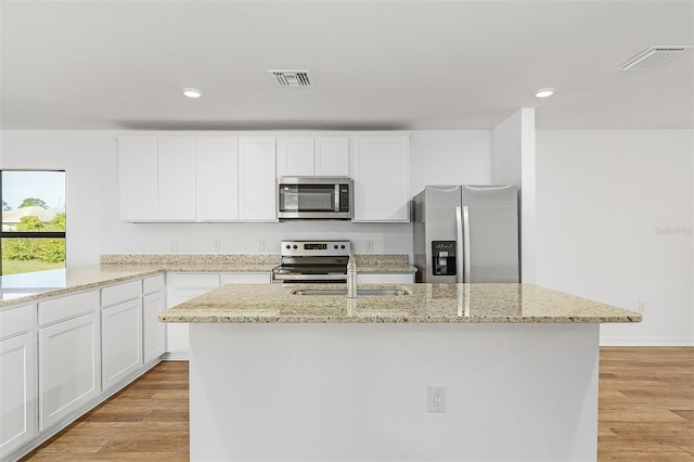 kitchen with light stone countertops, white cabinetry, appliances with stainless steel finishes, and light hardwood / wood-style flooring