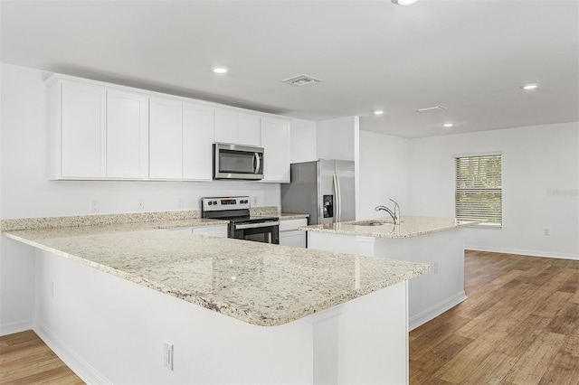 kitchen with white cabinetry, light stone countertops, sink, an island with sink, and appliances with stainless steel finishes