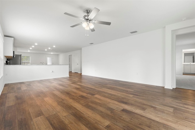 unfurnished living room featuring ceiling fan and dark hardwood / wood-style flooring