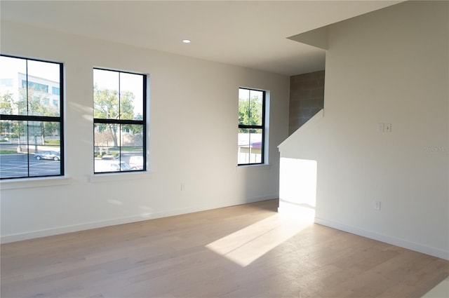 spare room featuring recessed lighting, light wood finished floors, and baseboards